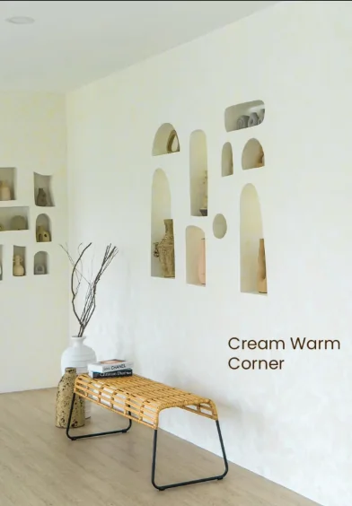 Cream corner wall with arched niches of vases and a rattan bench
